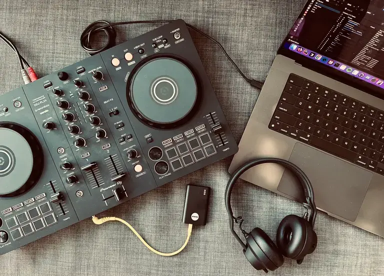DJ setup with controller, TMA-2 headphones, X03 transmitter, and laptop.